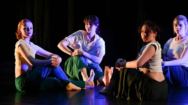 Eine Gruppe von Schülerinnen und Schülern der Cambridge School of Weston tritt auf einer Bühne mit bunter Beleuchtung auf.