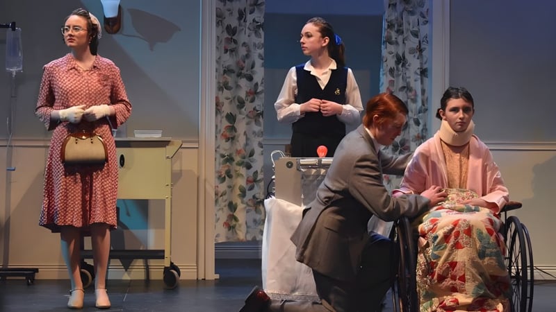 Vier Schülerinnen und Schüler der Camden Hills Regional High School spielen eine Theaterszene in historischen Kostümen in einem Raum mit floralen Vorhängen.