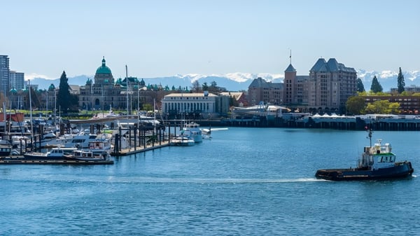 Blick auf einen Hafen mit Booten vor der Skyline und Bergen in der Umgebung des Camosun College.