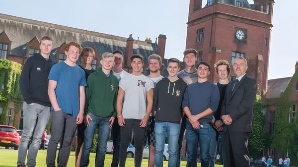 Eine Gruppe Schüler steht vor einem Backsteingebäude mit Uhrenturm auf dem Campus des Campbell College.