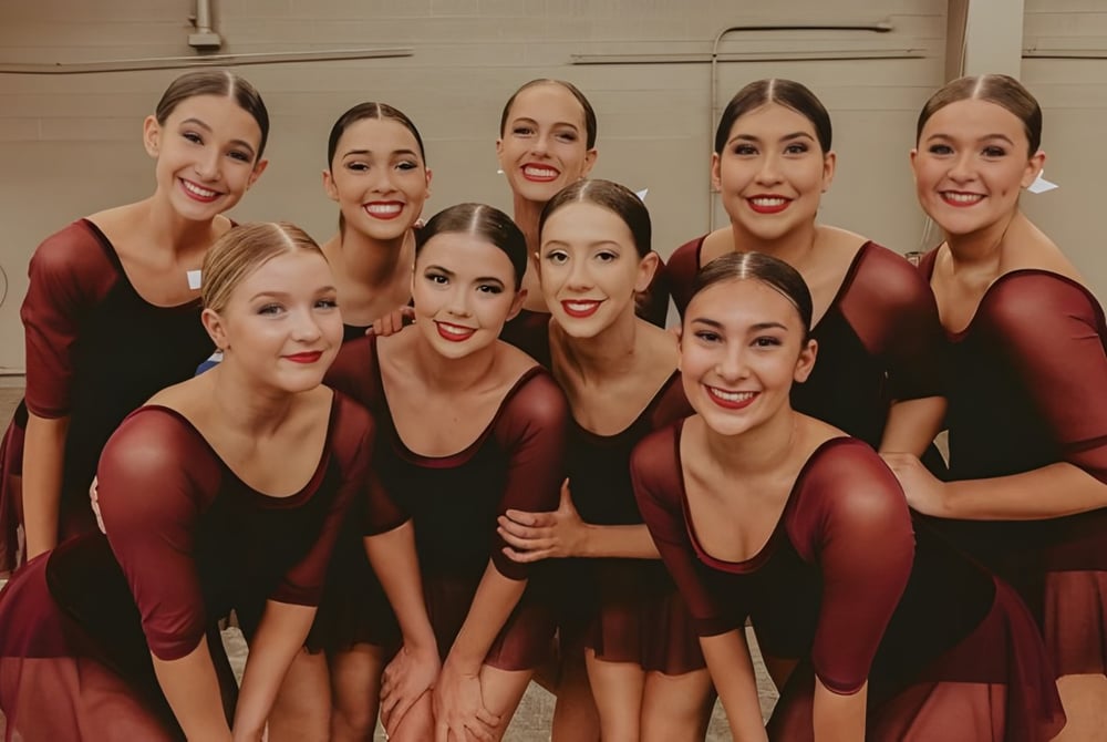 Eine Gruppe weiblicher Schülerinnen der Campo Verde High School posiert auf einer Bühne in roten und schwarzen Kleidern.
