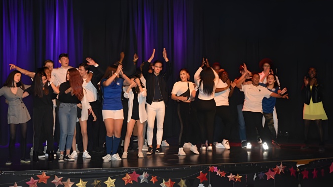 Eine Gruppe von Personen steht auf der Bühne am Campus La Salle Saint Christophe und hebt die Hände zum Applaus.