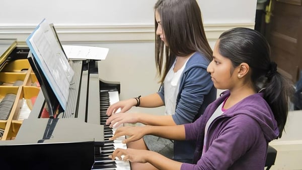 Zwei Schülerinnen spielen zusammen Klavier auf dem Campus der Canada Star Secondary School.