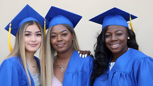 Drei Absolventinnen in blauen Talaren posieren gemeinsam vor neutralem Hintergrund auf der Canada Star Secondary School.