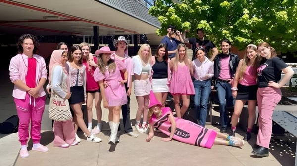 Eine Gruppe junger Frauen in verschiedenen Rosatönen steht vor einem Gebäude auf dem Campus des Canberra College.
