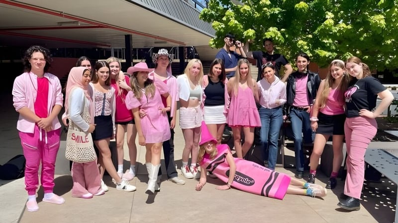 Eine Gruppe junger Frauen in verschiedenen Rosatönen steht vor einem Gebäude auf dem Campus des Canberra College.