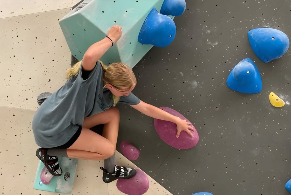Eine Schülerin klettert an der bunten Kletterwand im Kletterbereich des Canberra College.