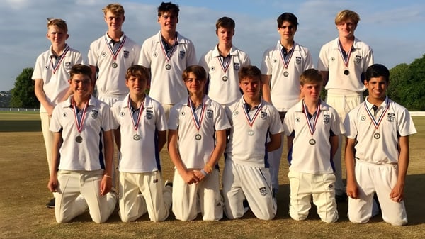 Eine Gruppe Schüler der Canford School steht im Cricket-Uniform auf einem Rasenfeld unter klarem Himmel.
