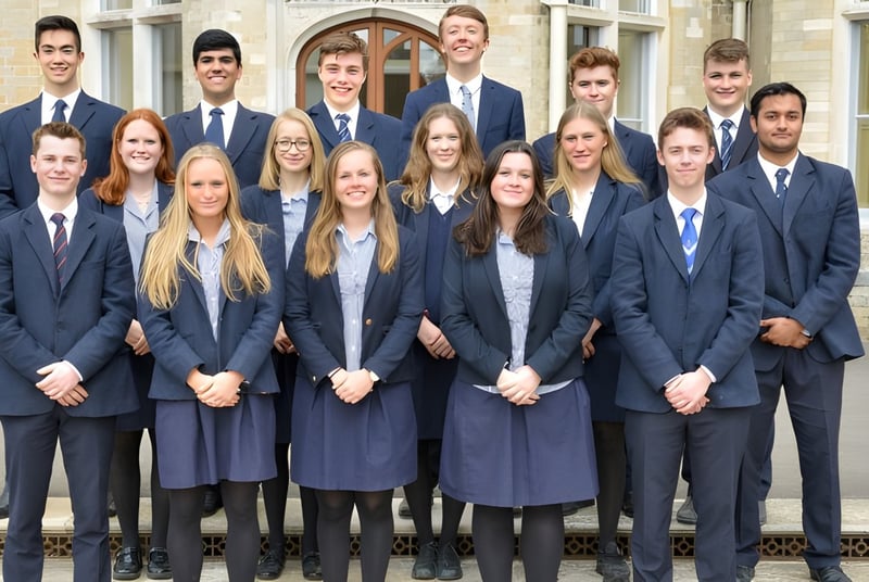 Eine Gruppe Schülerinnen und Schüler der Canford School steht in formeller Kleidung vor einem historischen Gebäude.