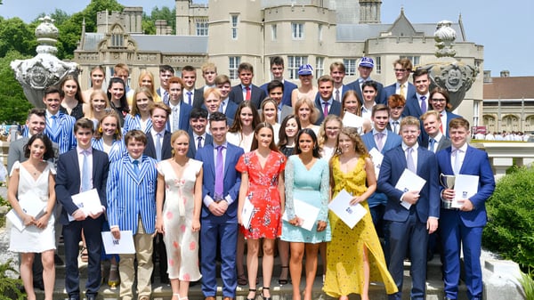 Eine große Gruppe von Menschen in formaler Kleidung steht vor dem Schlossgebäude der Canford School für ein Gruppenfoto.