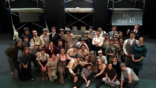 Schüler der Canmore Collegiate High School treten auf einer Bühne vor einem Hintergrund mit der Aufschrift The World auf.