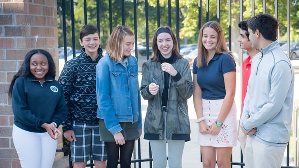 Eine Gruppe Schülerinnen und Schüler steht vor einem Backsteingebäude auf dem Campus der Canterbury High School.