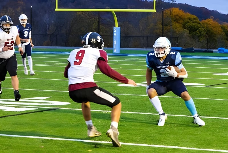 Zwei Football-Spieler laufen auf dem Spielfeld der Canterbury School mit herbstlichem Laub im Hintergrund.