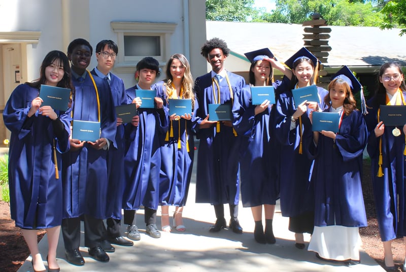 Absolventinnen und Absolventen der Canyonville Academy stehen in blauen Talaren gemeinsam vor einem Gebäude mit Bäumen.