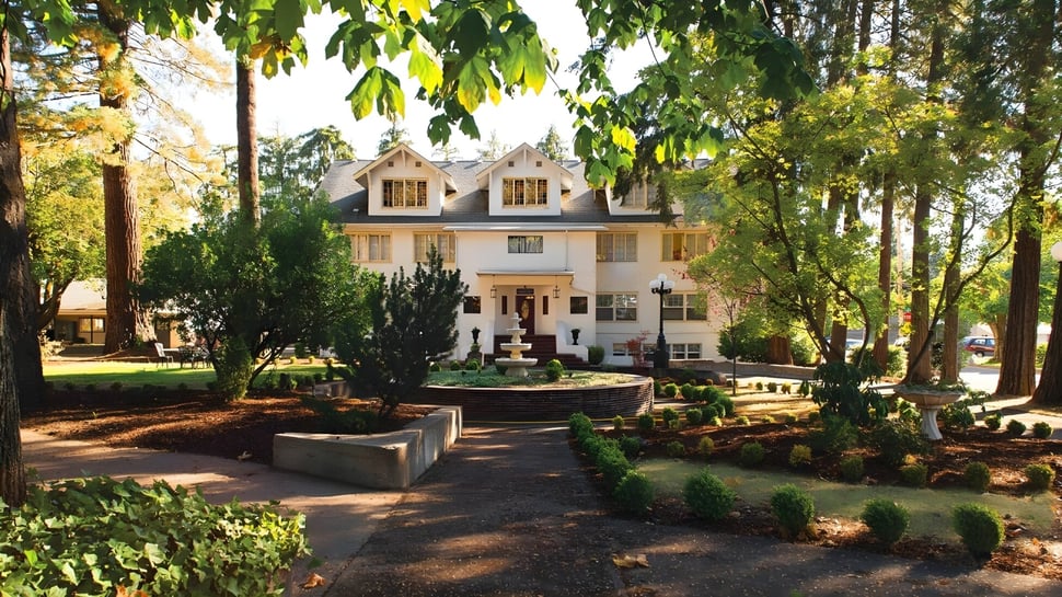 Ein viktorianisches Haus auf dem Campus der Canyonville Academy ist von üppigem Grün umgeben.
