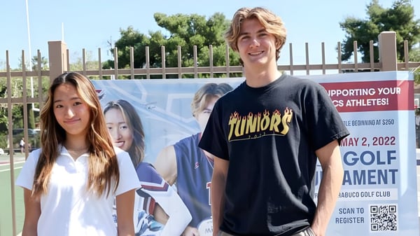 Zwei Schülerinnen und Schüler stehen vor einem Banner für eine Golfveranstaltung auf dem Campus der Capistrano Valley Christian.