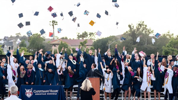 Absolventinnen und Absolventen der Capistrano Valley Christian School feiern ihren Abschluss vor Palmen und Schulgebäuden.