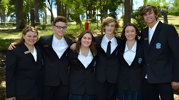 Eine Gruppe Schüler der Cardiff High School steht in Schuluniformen in einem Wald und posiert für ein Foto.