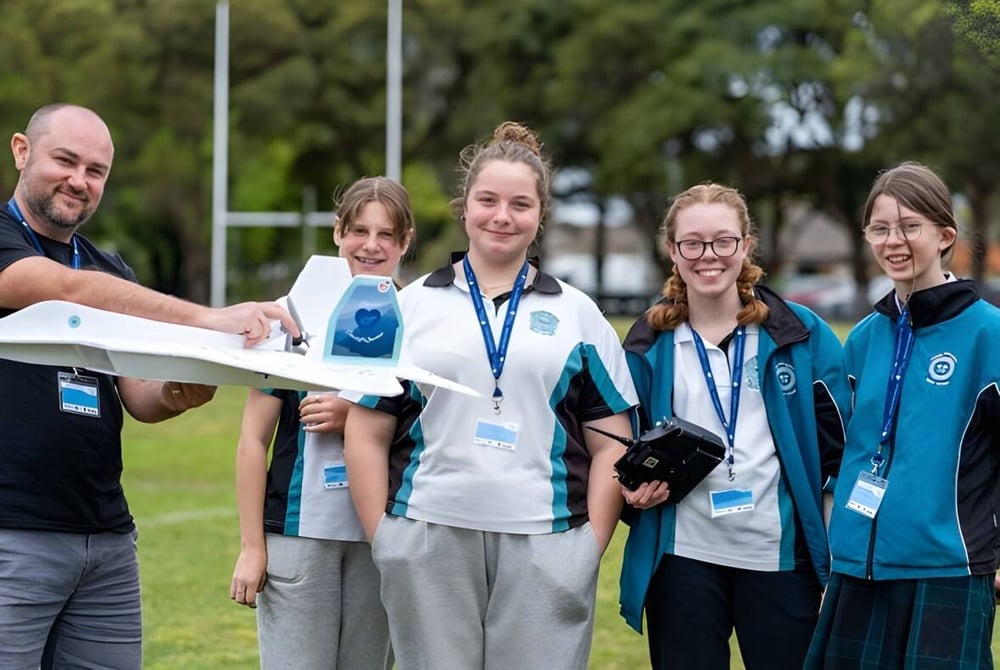 Schüler und Lehrkräfte der Cardiff High School stehen gemeinsam auf einem Sportfeld im Freien.