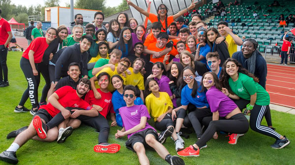 Eine Gruppe Schülerinnen trägt bunte Sportkleidung und posiert für ein Gruppenfoto auf dem Sportplatz des Cardiff Sixth Form College.