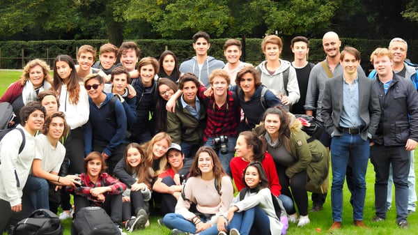 Eine Gruppe Schülerinnen und Schüler von Carfax College versammelt sich im Freien vor Bäumen und Grünflächen.