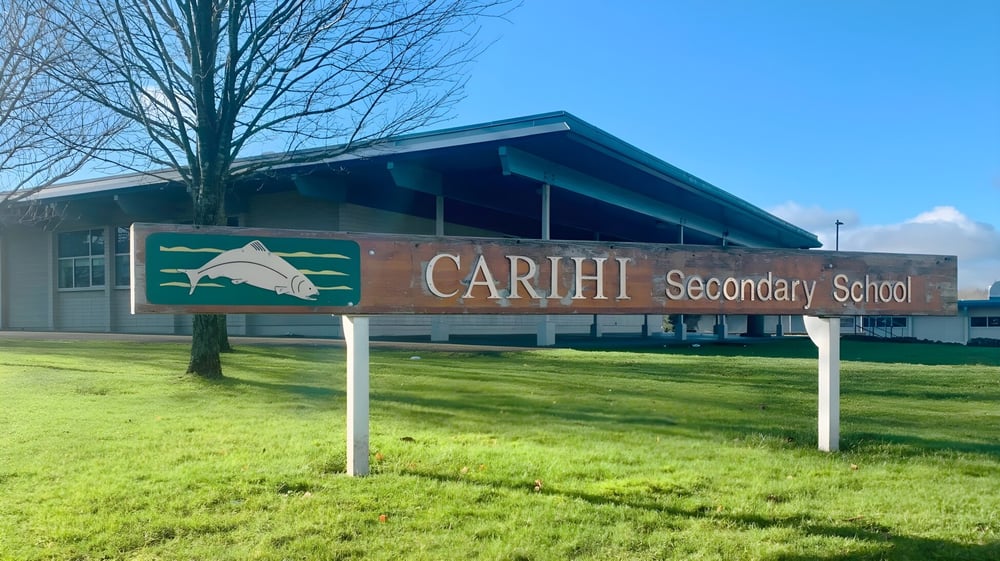Das Gebäude der Carihi Secondary School steht vor einem Grasfeld und blauem Himmel.
