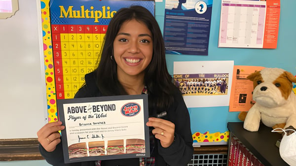 Eine Schülerin der Carl Schurz High School hält in einem Klassenraum ein Buch mit dem Titel Above & Beyond: Players of the Week.