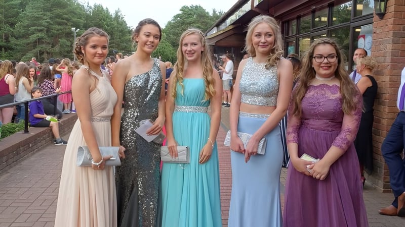 Eine Gruppe Schülerinnen des Carmel College steht in formeller Kleidung vor einem Backsteingebäude bei einer feierlichen Veranstaltung.