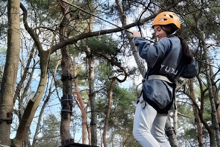 Eine Schülerin mit Schutzhelm und Sicherungsgurt klettert auf dem Gelände der Carmelitas Cadiz Colegio auf einen Baum.