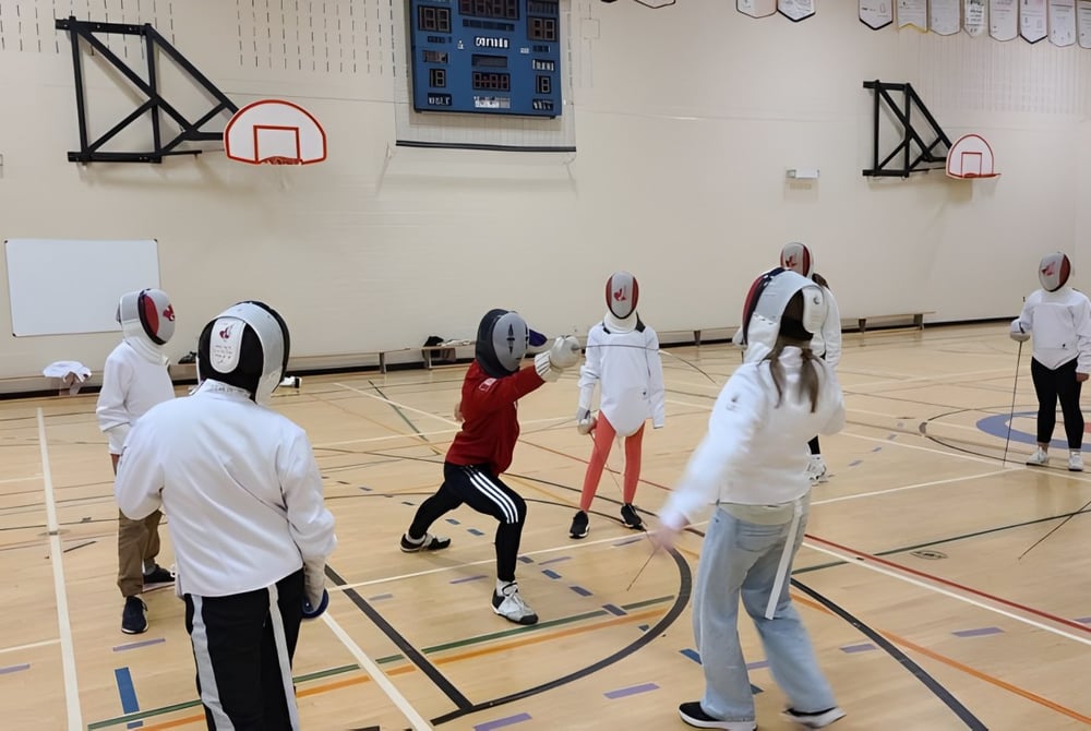 Eine Gruppe Schüler in der Turnhalle mit Basketballkörben auf dem Campus der Carrefour de l’Acadie.