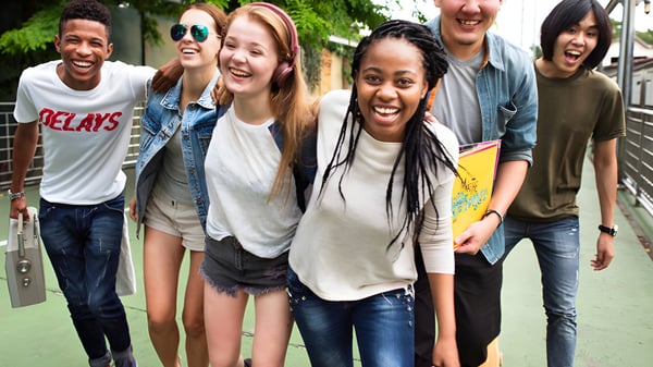 Eine Gruppe Schülerinnen und Schüler der École secondaire publique Carrefour Jeunesse steht im Freien vor einer grünen Kulisse.