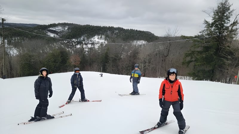 Schüler der École secondaire publique Carrefour Jeunesse beim Skifahren auf einer verschneiten Bergpiste umgeben von Wald.