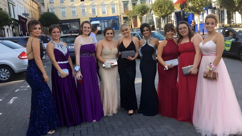 Eine Gruppe junger Frauen in festlicher Kleidung steht auf der Straße vor dem Carrignafoy Community College.