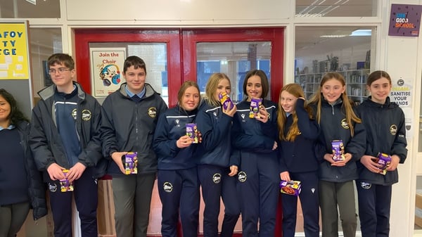 Schüler des Carrignafoy Community College stehen gemeinsam im Schulflur mit einheitlicher Schuluniform.