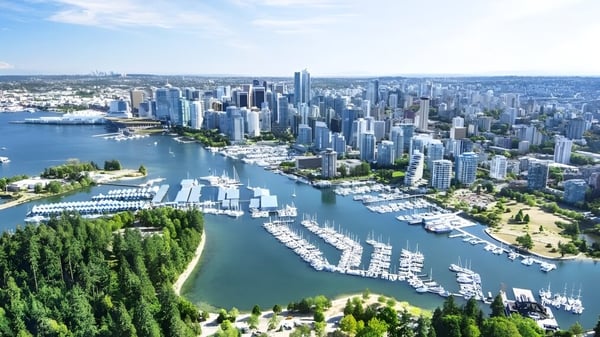Eine weite Stadtsilhouette mit großen Wolkenkratzern und einem belebten Hafen zeigt sich nahe der Carson Graham Secondary School.