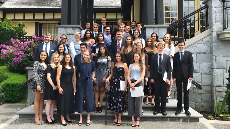Eine Gruppe von Schülerinnen und Schülern steht gemeinsam auf der Treppe eines historischen Gebäudes auf dem Campus der Carson Graham Secondary School.