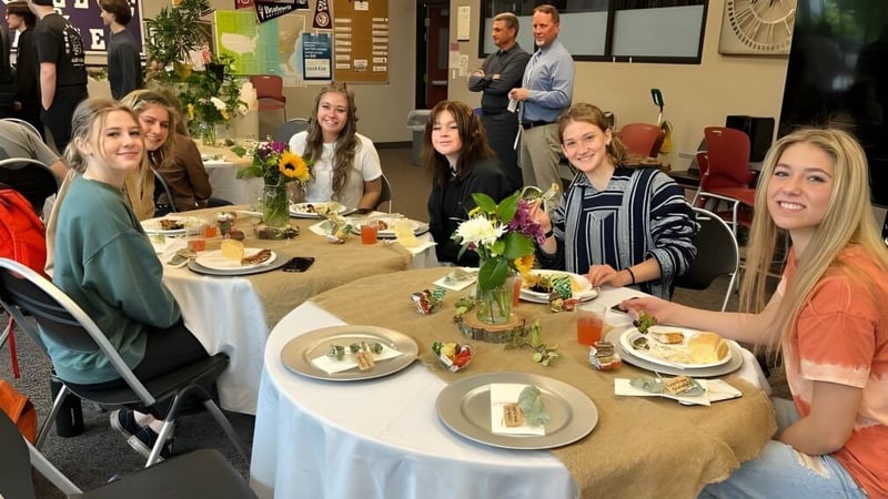 Schüler der Cascade Christian High School sitzen gemeinsam an einem Tisch und essen in festlicher Umgebung.