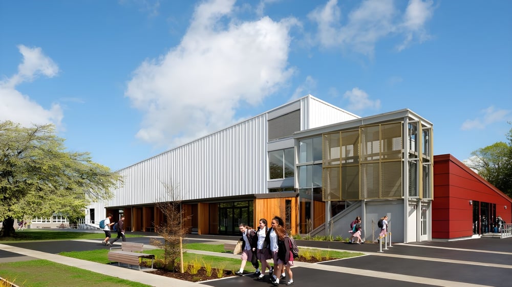 Gebäude der Cashmere High School mit moderner Architektur und einer begrünten Außenanlage, Menschen gehen auf dem Weg davor.