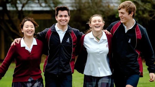 Eine Gruppe von Schülern steht auf dem Campus der Cashmere High School im Freien auf einer Wiese mit Bäumen im Hintergrund.