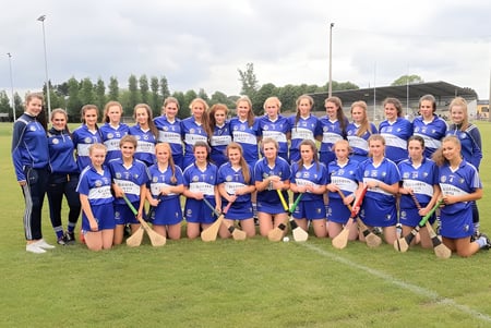 Eine Gruppe von jungen Fußballspielerinnen in blauen Trikots auf dem Sportplatz des Castlepollard Community College.