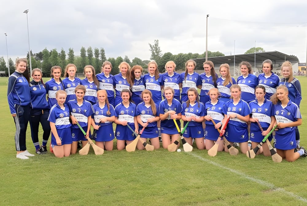 Eine Gruppe von jungen Fußballspielerinnen in blauen Trikots auf dem Sportplatz des Castlepollard Community College.