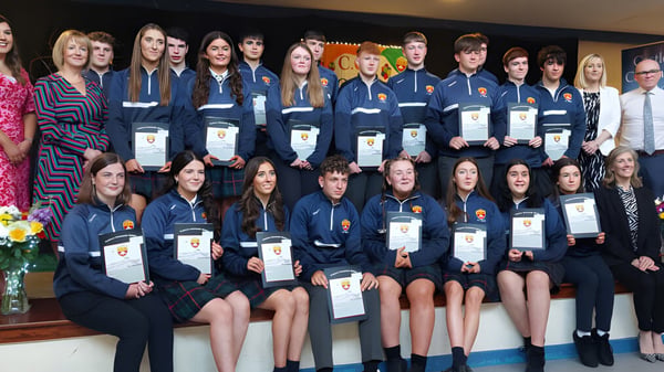 Schüler der Castlerea Community School tragen einheitliche Uniformen und halten Auszeichnungen in einem formellen Rahmen.