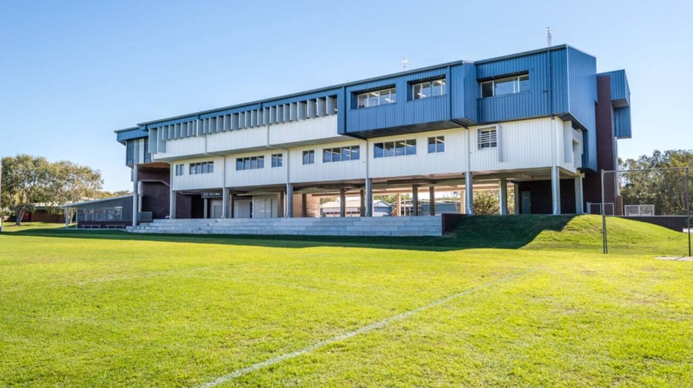 Das moderne mehrstöckige Gebäude der Castlerea Community School steht auf einem grünen Feld unter blauem Himmel.