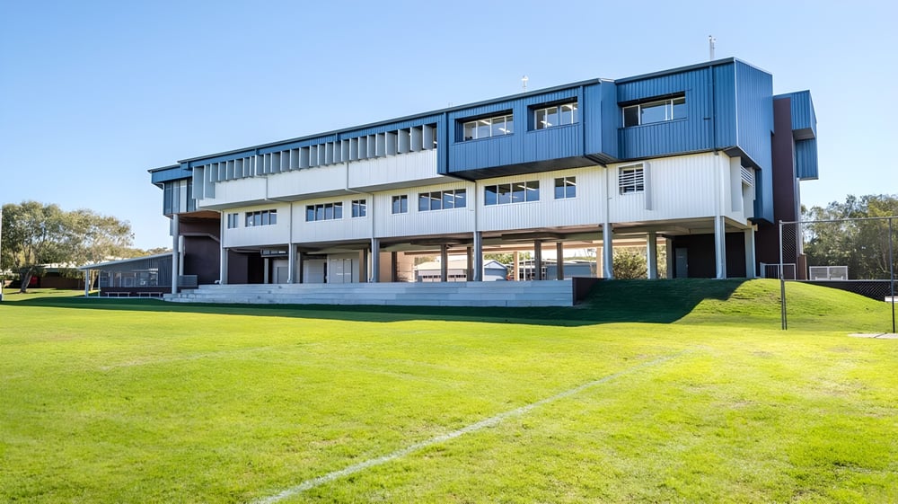 Das moderne mehrstöckige Gebäude der Castlerea Community School steht auf einer Wiese umgeben von Bäumen unter blauem Himmel.