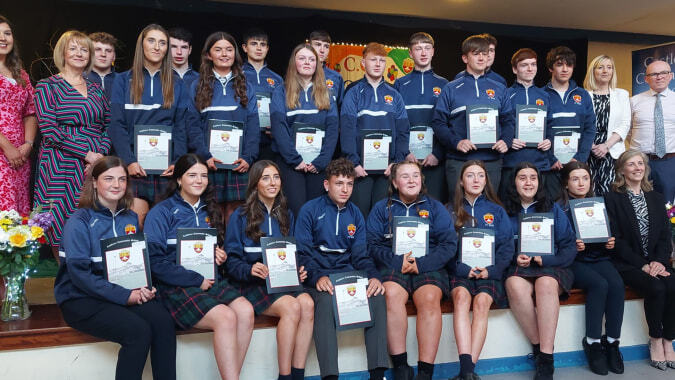 Eine Gruppe Schülerinnen der Castlerea Community School posiert mit Zertifikaten vor einem formalen Hintergrund.