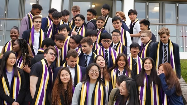Schüler der Caterham School stehen in ihren Abschlussroben vor einem Gebäude mit großen Fenstern.