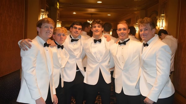 Eine Gruppe von Männern in weißen Smokingjacken und schwarzen Fliegen im Flur der Cathedral Preparatory School.