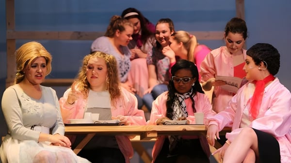 Schülerinnen und Schüler der Cathedral Preparatory School sitzen in einer Gruppenrunde an einem Tisch vor einem Hintergrund mit blauem Himmel.