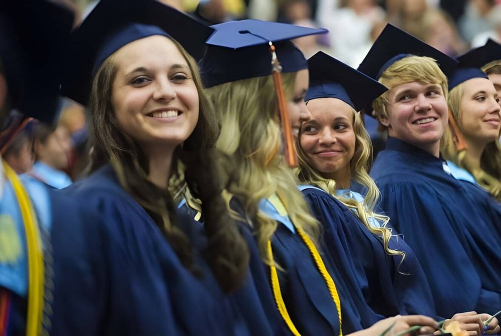 Absolventinnen und Absolventen der Catholic Central High School stehen in ihren blauen und gelben Talaren gemeinsam in einer Gruppe.