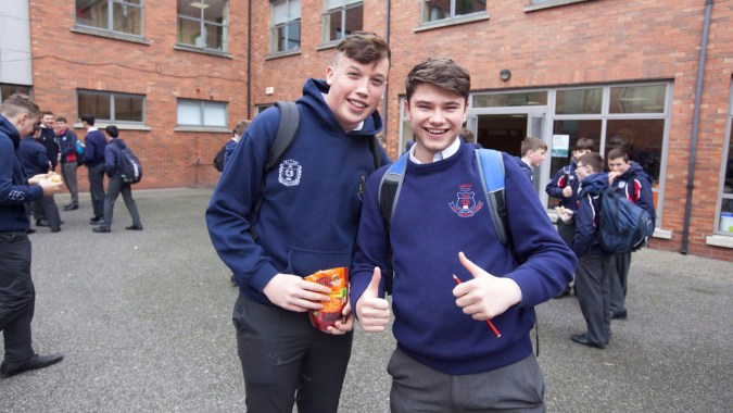Zwei Schüler in Schuluniformen stehen vor einem Backsteingebäude auf dem Campus der Catholic University School.
